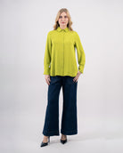 Chemise fluide femme vert lime avec col classique et boutons apparents portée avec jean large-vue de face