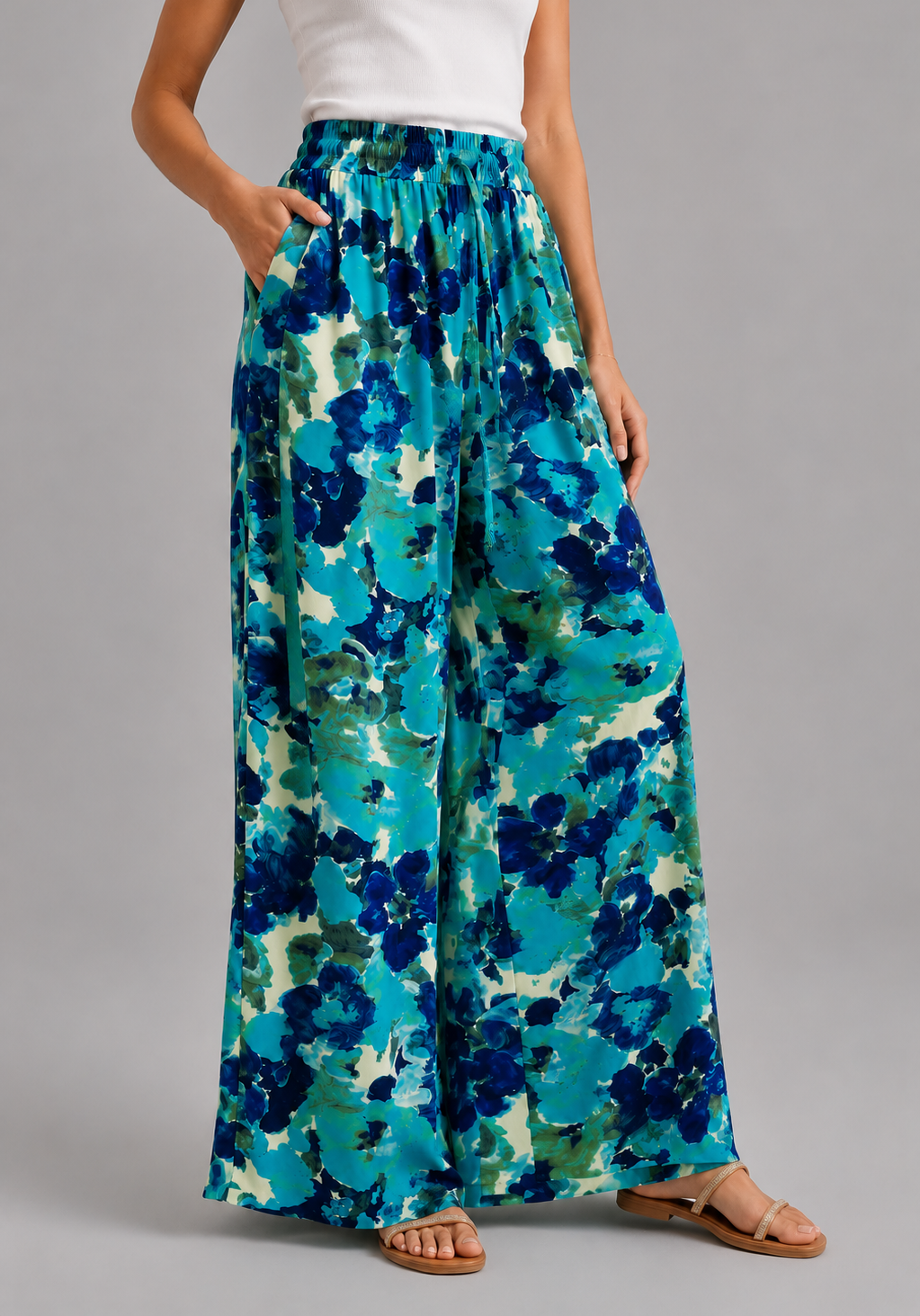 Pantalon large femme à imprimé floral bleu turquoise porté avec débardeur blanc sur fond gris-vue de cote