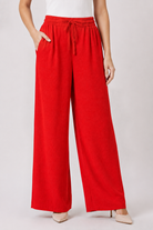 Pantalon large fluide orange pour femme avec taille haute élastiquée et cordon ajustable.