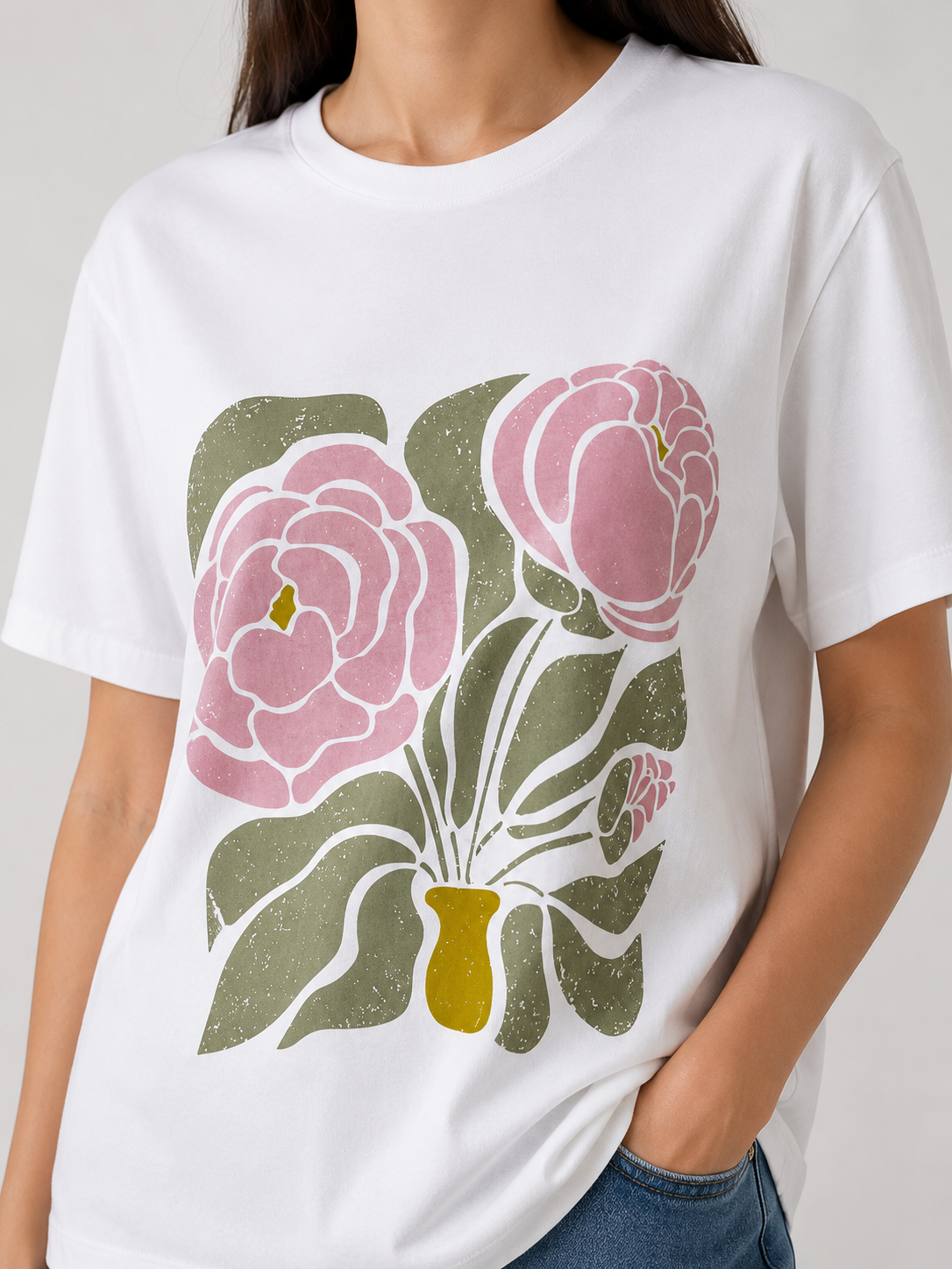 Détail du t-shirt blanc RAZANA avec imprimé floral rose, vert olive et vase jaune